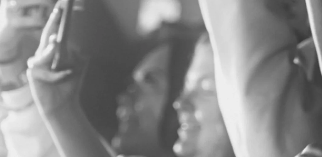 Audience members with raised hands and phones at a lively concert in the O2 Academy Birmingham. Black and white photo.